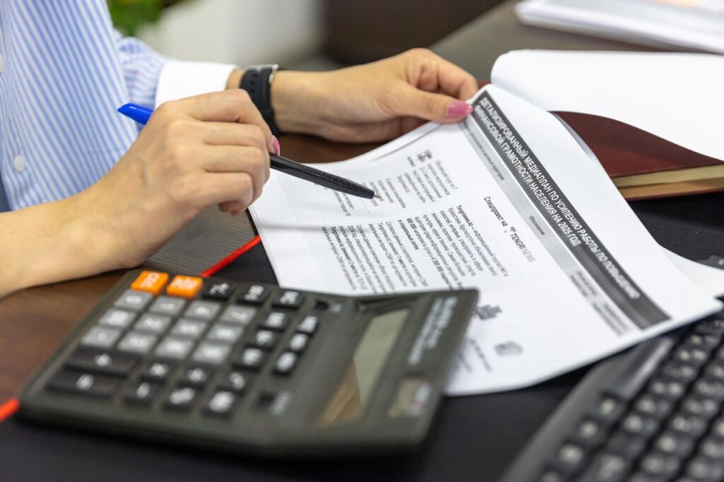 Home Close-up of a person analyzing financial documents using a calculator and pen.