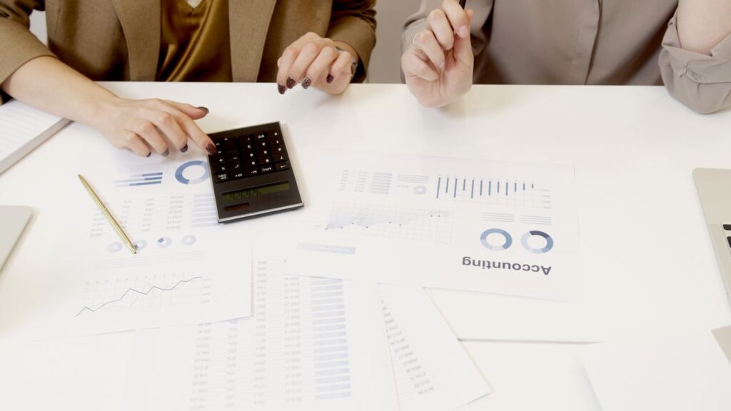 Home Two professionals analyzing financial documents with a calculator.