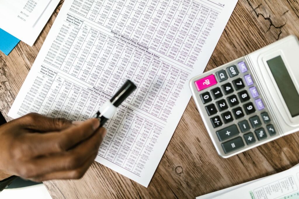 Home Close-up of tax documents and calculator on wooden table, highlighting financial analysis.