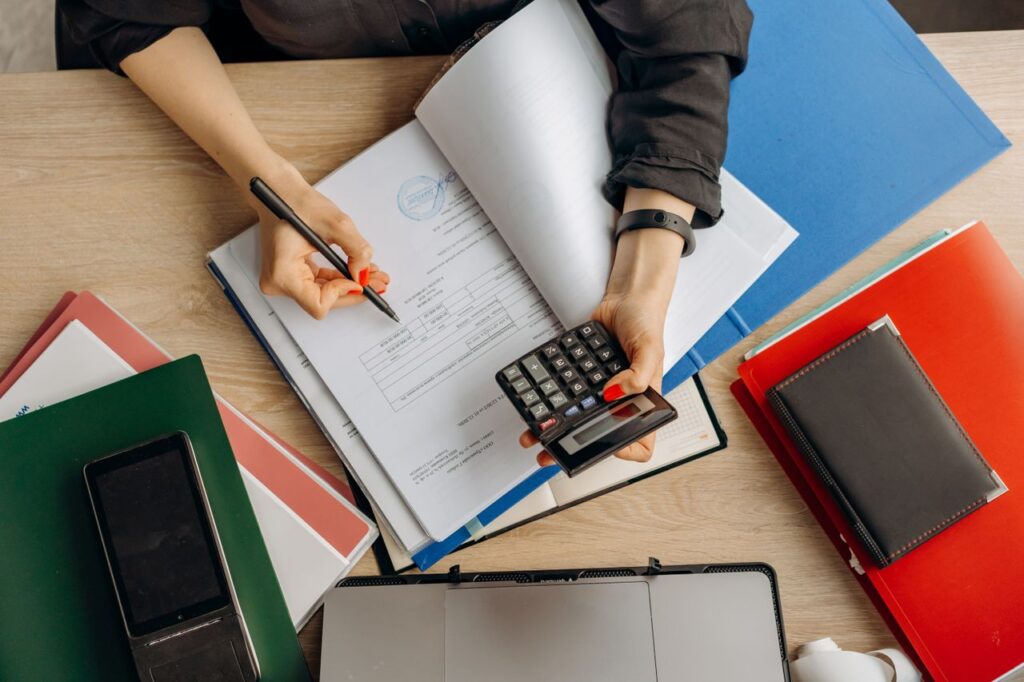Home Accountant analyzing financial documents with a calculator on a desk, highlighting business tasks.