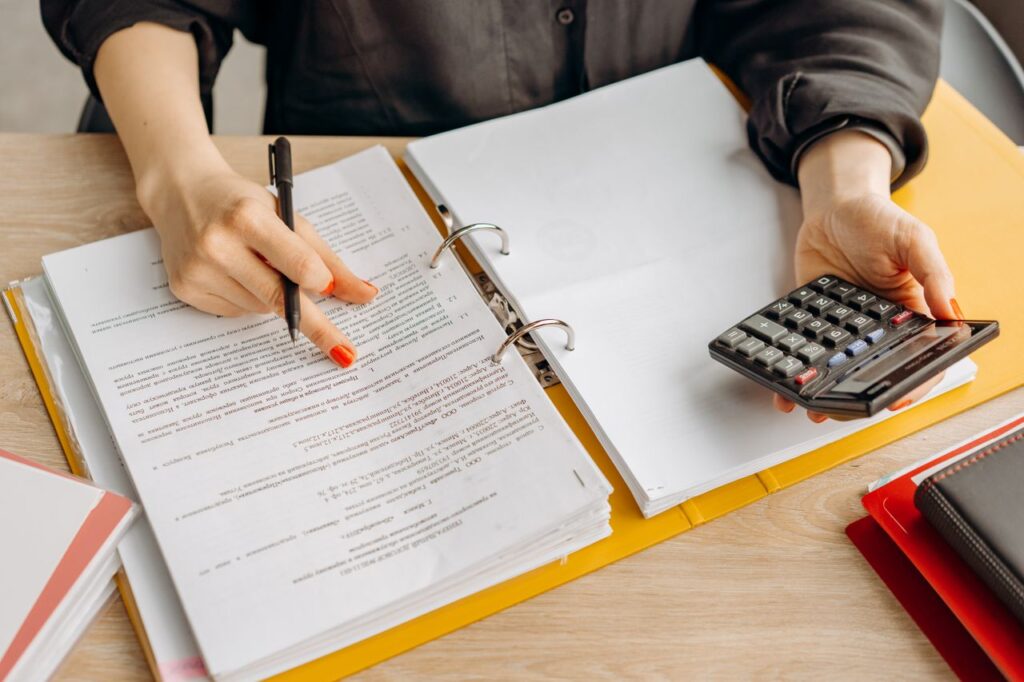 Home A woman reviewing documents and using a calculator on a wooden table.